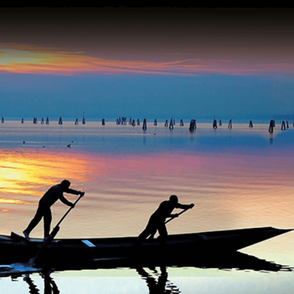 Gondoliers sur la lagune de Venise au soleil couchant